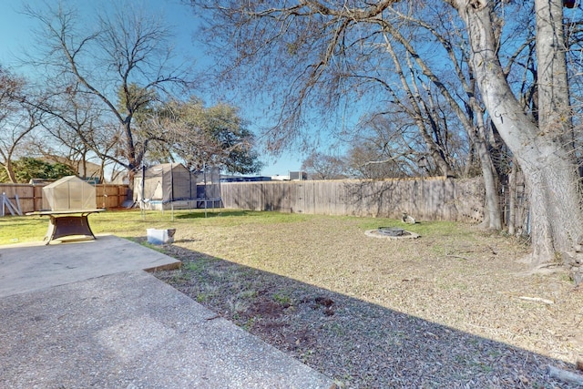 view of yard featuring a trampoline, a patio area, and an outdoor fire pit