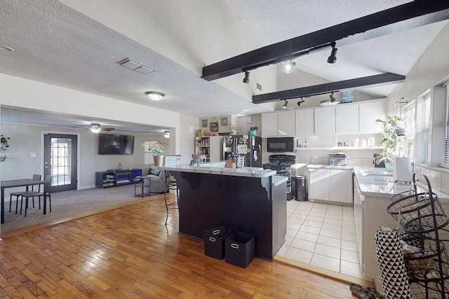 kitchen featuring white cabinetry, plenty of natural light, lofted ceiling, and a textured ceiling