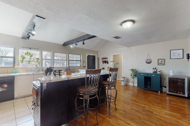 kitchen with blue cabinetry, white cabinetry, a kitchen breakfast bar, black dishwasher, and a textured ceiling