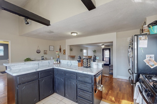 kitchen with gas range, kitchen peninsula, and a textured ceiling