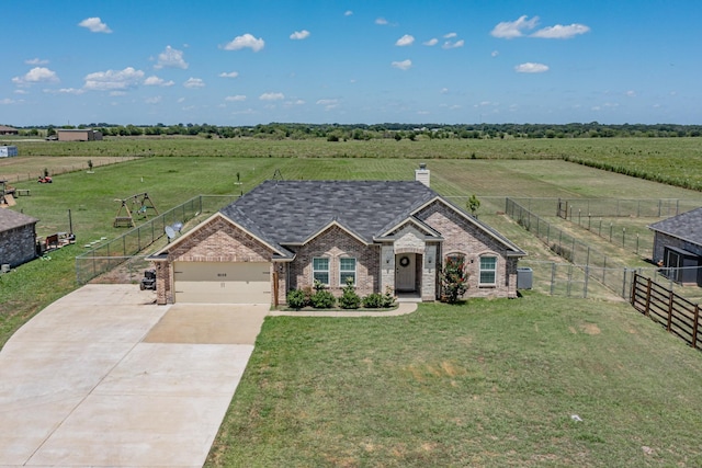 view of front of property featuring a garage, a front lawn, and a rural view