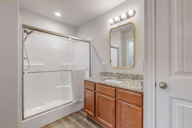 bathroom with wood-type flooring, a shower with door, and vanity