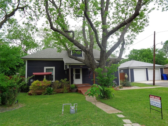 view of front of property featuring an outbuilding, a front lawn, and a garage