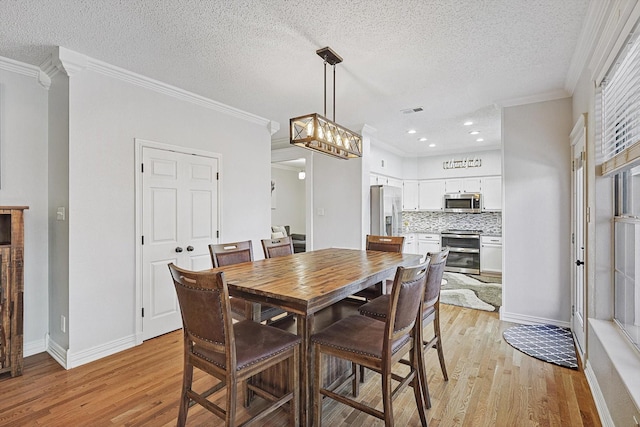 dining room featuring crown molding, a textured ceiling, and light wood-type flooring