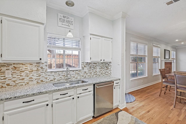 kitchen with pendant lighting, dishwasher, sink, white cabinets, and crown molding