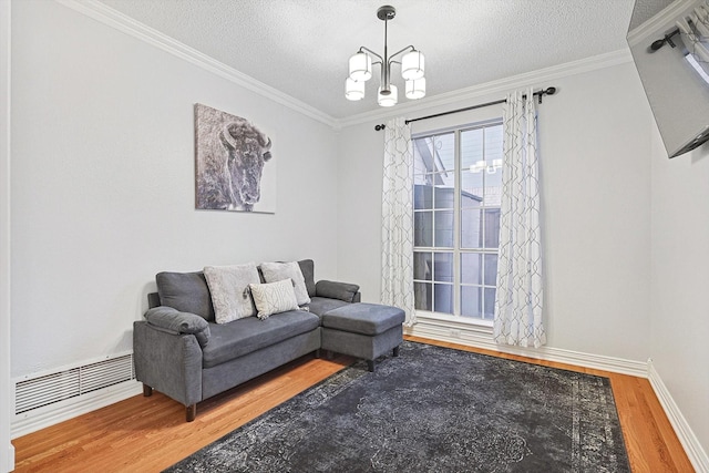 living room featuring an inviting chandelier, ornamental molding, hardwood / wood-style floors, and a textured ceiling