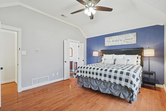 bedroom with ensuite bath, vaulted ceiling, ornamental molding, ceiling fan, and hardwood / wood-style floors