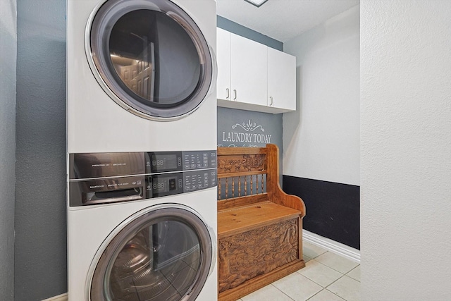 laundry area with cabinets, stacked washer and clothes dryer, and light tile patterned floors