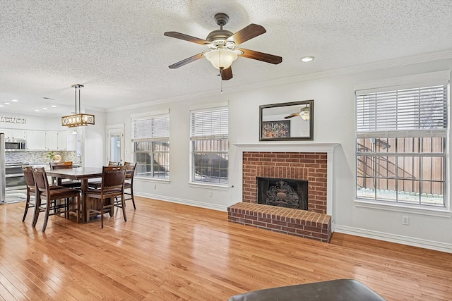 living room with ornamental molding, a fireplace, light hardwood / wood-style flooring, and plenty of natural light