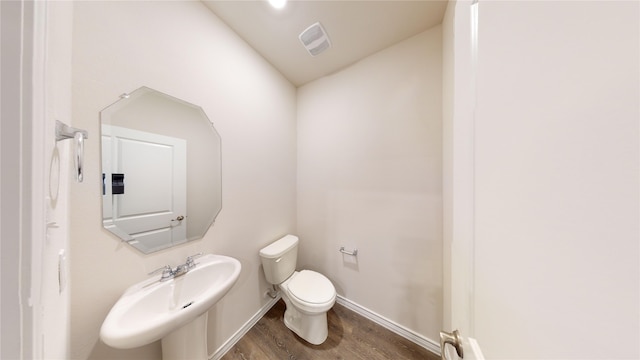 bathroom featuring sink, hardwood / wood-style floors, toilet, and vaulted ceiling