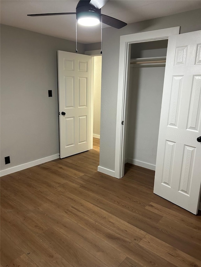 unfurnished bedroom featuring ceiling fan, a closet, and dark hardwood / wood-style flooring