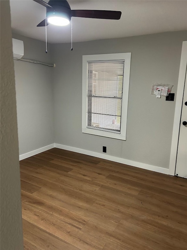 spare room featuring ceiling fan, wood-type flooring, and an AC wall unit