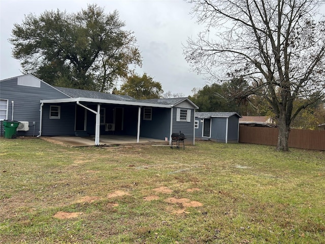 rear view of house featuring a patio, a lawn, and a shed