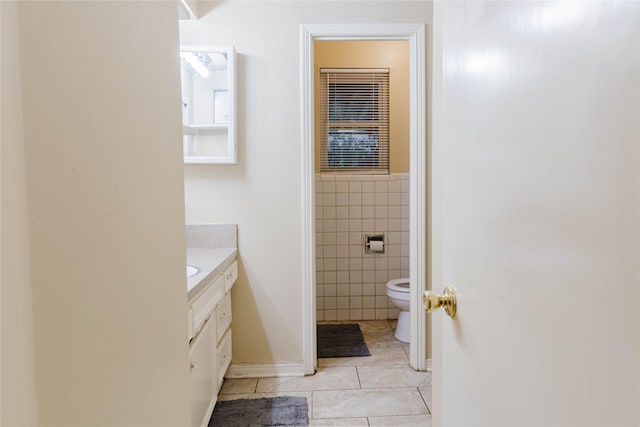 bathroom with toilet, vanity, tile patterned flooring, and tile walls