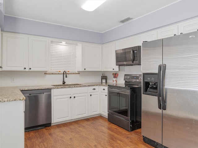 kitchen with white cabinets, sink, stainless steel appliances, and hardwood / wood-style flooring