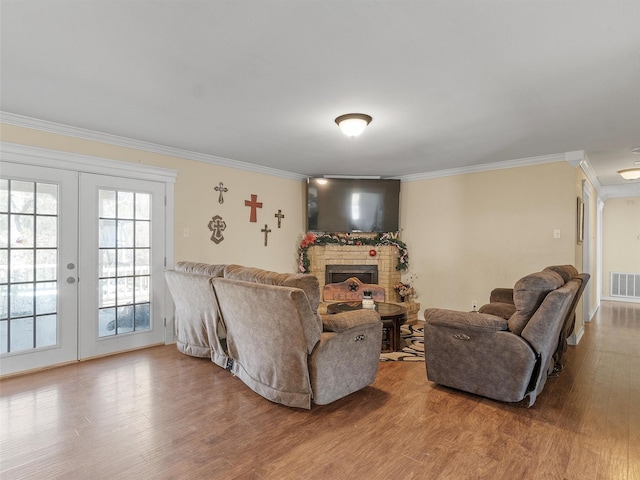 living room featuring french doors, a fireplace, ornamental molding, and wood-type flooring