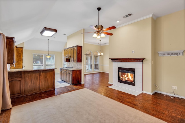 kitchen featuring vaulted ceiling, hardwood / wood-style floors, a fireplace, tasteful backsplash, and kitchen peninsula