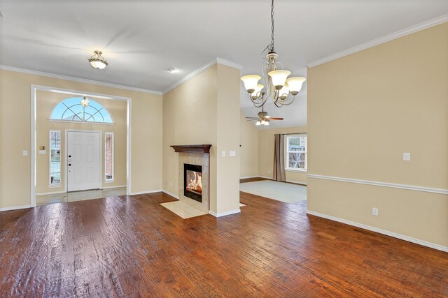 unfurnished living room with a tiled fireplace, crown molding, hardwood / wood-style floors, and an inviting chandelier