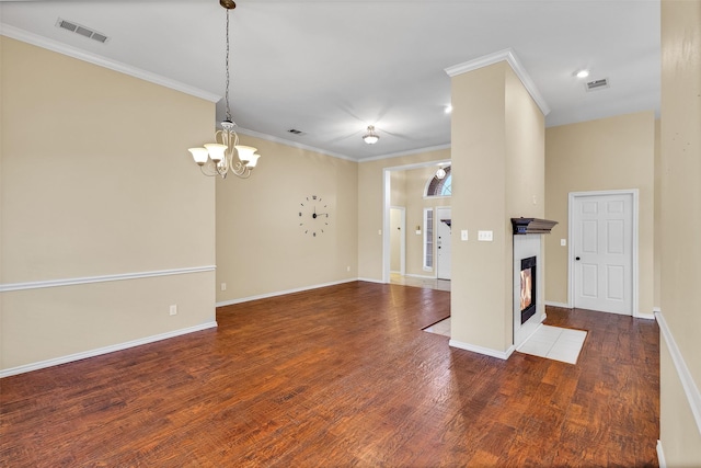 interior space with an inviting chandelier, ornamental molding, a tile fireplace, and dark hardwood / wood-style floors