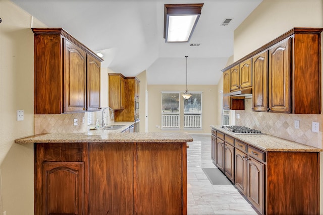 kitchen with lofted ceiling, sink, light stone counters, kitchen peninsula, and stainless steel appliances