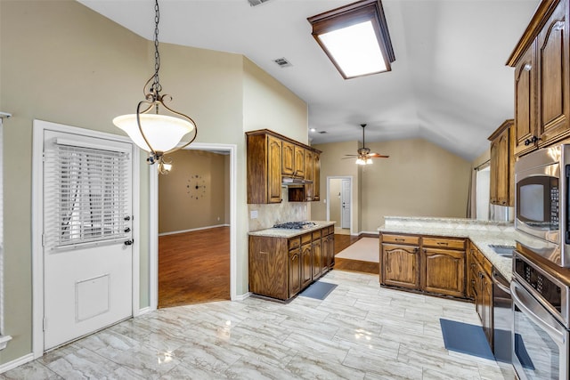 kitchen featuring lofted ceiling, ceiling fan, appliances with stainless steel finishes, hanging light fixtures, and light stone counters