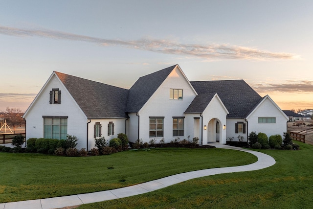 view of front of home with a yard and a shingled roof