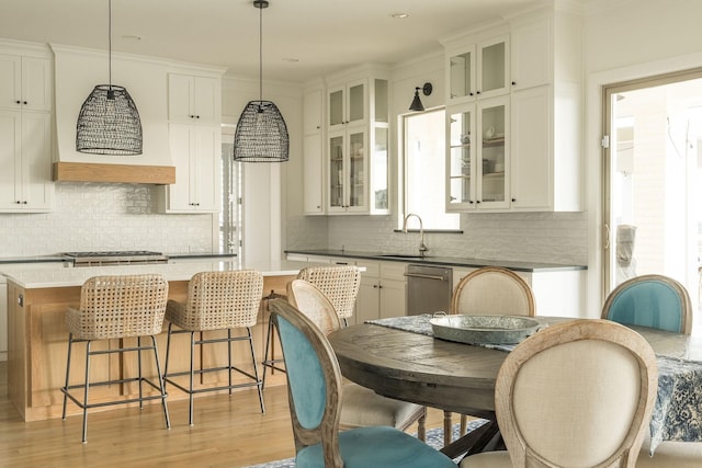 kitchen featuring light wood-style flooring, stainless steel appliances, a kitchen island, a kitchen breakfast bar, and backsplash