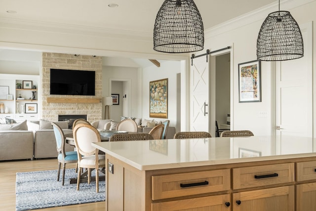 kitchen with a barn door, light wood-style flooring, open floor plan, light countertops, and ornamental molding