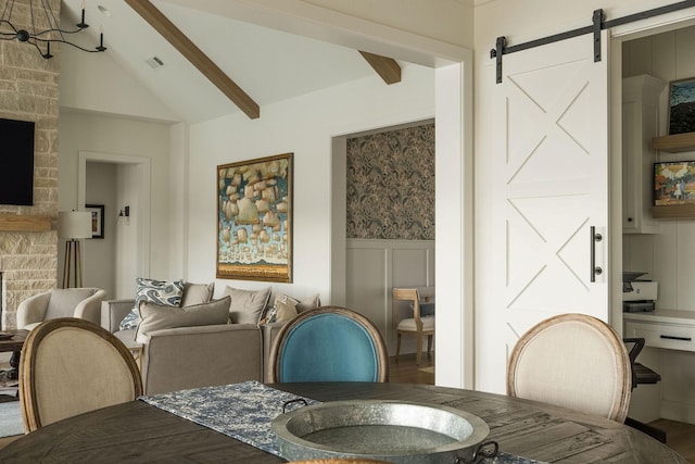 dining space with a wainscoted wall, visible vents, vaulted ceiling with beams, and a barn door