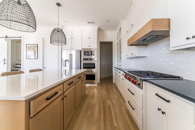 kitchen with visible vents, decorative backsplash, appliances with stainless steel finishes, light wood-style floors, and premium range hood