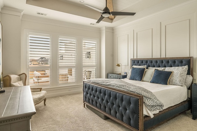 bedroom with light carpet, visible vents, a ceiling fan, a tray ceiling, and crown molding