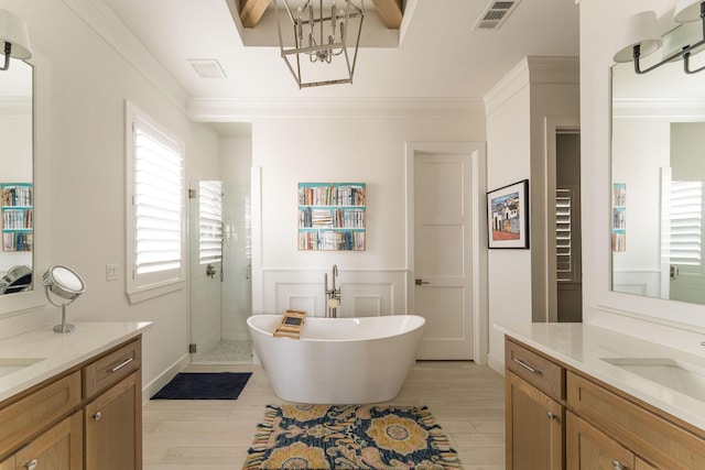 full bath with visible vents, wood finished floors, crown molding, a shower stall, and two vanities