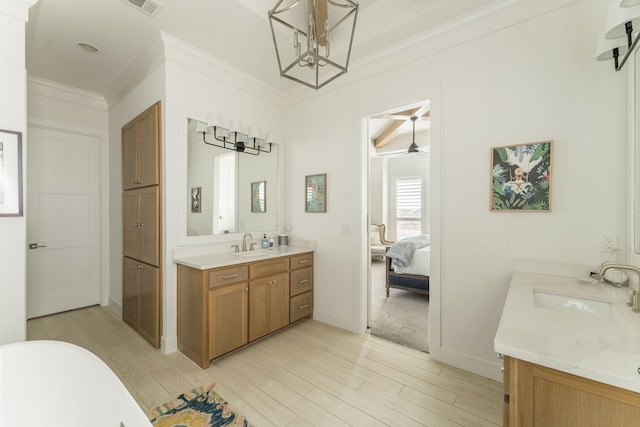 ensuite bathroom featuring two vanities, a sink, and wood finished floors