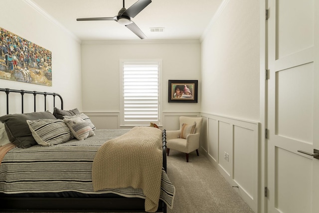 bedroom featuring a decorative wall, a wainscoted wall, visible vents, carpet, and crown molding