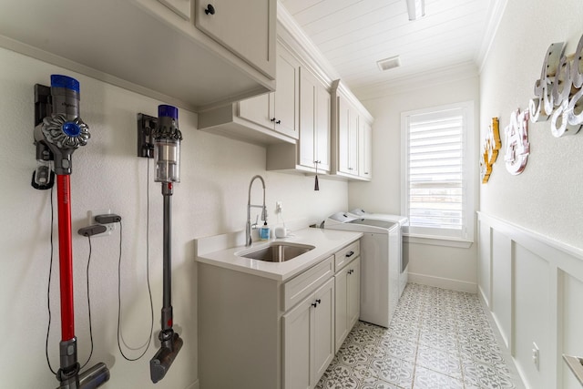 clothes washing area featuring a sink, visible vents, washer and dryer, cabinet space, and crown molding