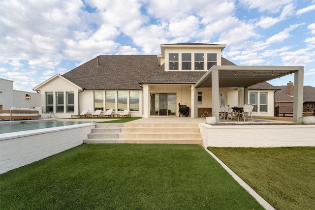 rear view of house with a shingled roof, an outdoor pool, a patio area, and a yard