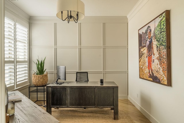 home office featuring crown molding, baseboards, a decorative wall, and wood finished floors