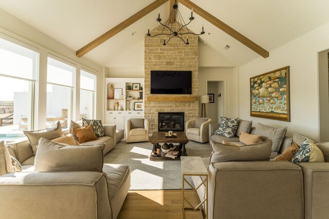 living room with built in shelves, light wood-type flooring, vaulted ceiling with beams, and a stone fireplace