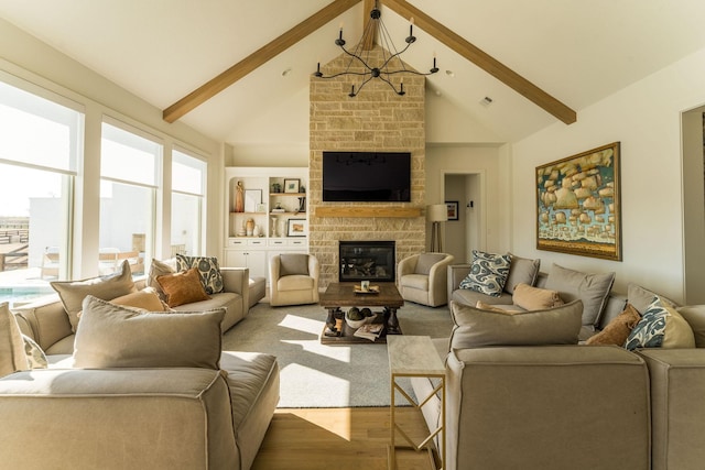 living area featuring light wood finished floors, beam ceiling, a notable chandelier, a stone fireplace, and high vaulted ceiling