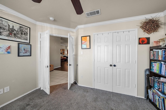 carpeted bedroom featuring ceiling fan, a closet, and crown molding