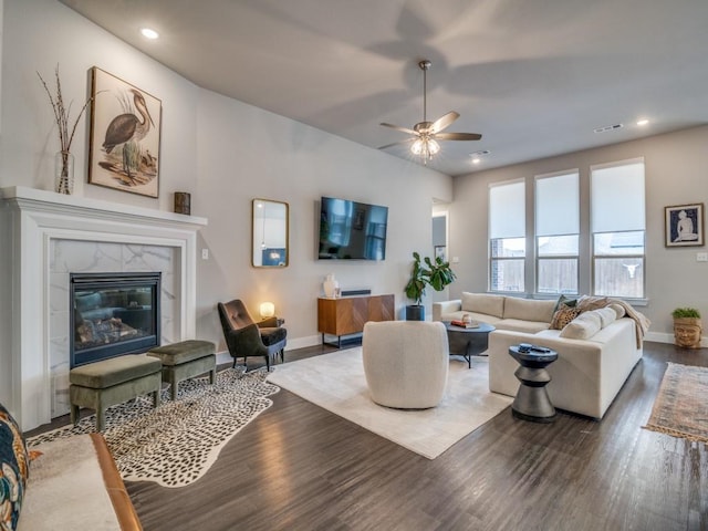 living room featuring ceiling fan, a high end fireplace, and hardwood / wood-style flooring