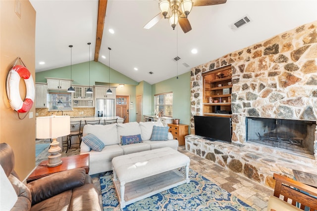 living room with ceiling fan, sink, built in features, beam ceiling, and a stone fireplace