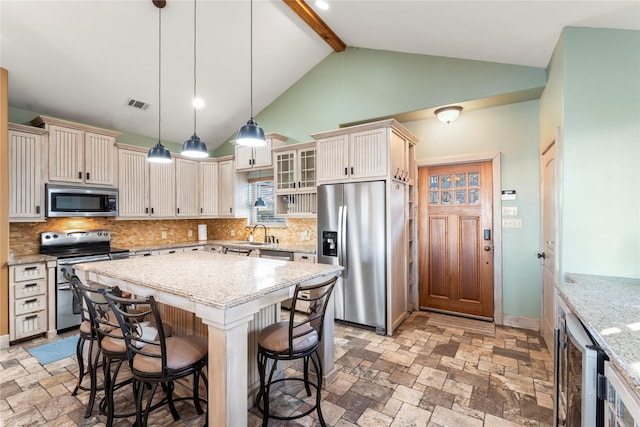 kitchen with backsplash, light stone counters, a kitchen island, beamed ceiling, and stainless steel appliances