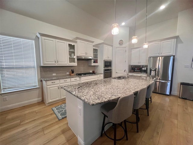 kitchen with a center island with sink, a kitchen bar, sink, white cabinetry, and stainless steel appliances