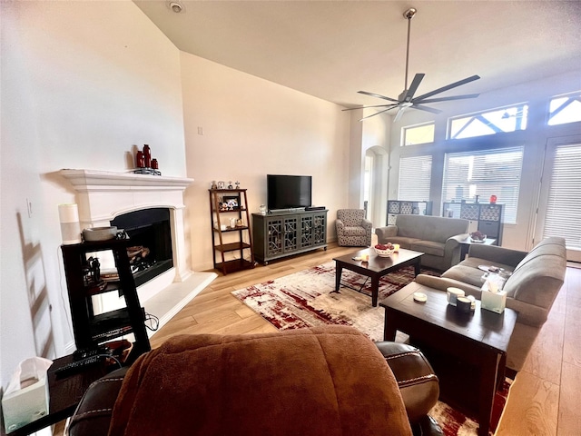 living room with ceiling fan, vaulted ceiling, and light hardwood / wood-style floors