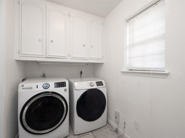 laundry area featuring cabinets, light tile patterned flooring, and separate washer and dryer