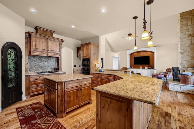 kitchen featuring tasteful backsplash, a center island, black appliances, kitchen peninsula, and light stone countertops