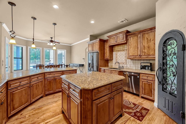 kitchen with ceiling fan, a kitchen island, decorative backsplash, sink, and stainless steel appliances