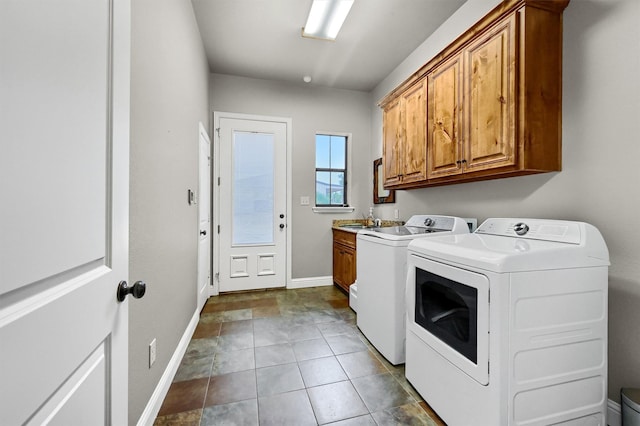 laundry room with cabinets, dark tile patterned flooring, separate washer and dryer, and sink