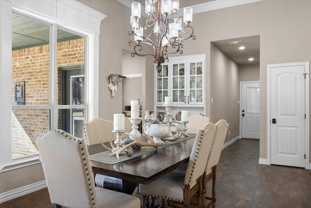 dining area with dark hardwood / wood-style floors, crown molding, and an inviting chandelier